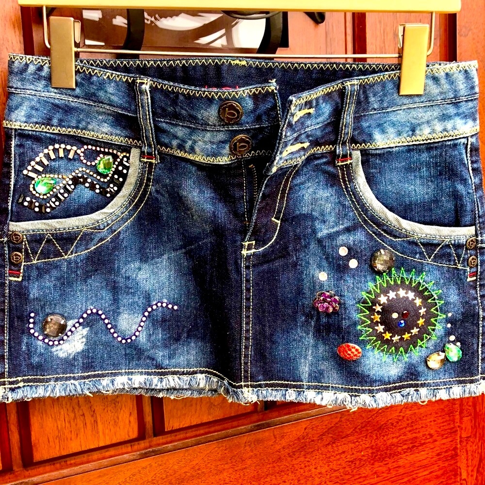Bebe embellished denim skirt with buttons and colorful decorative details.